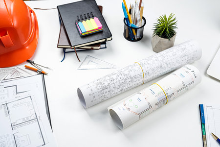 Housing project blueprints with hardhat and tools on office workplace. Construction concepts