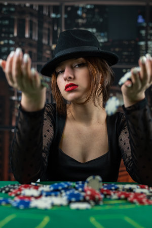 female hand takes poker chips from a pile at a round poker table. risky bets in poker. woman in casino.の写真素材