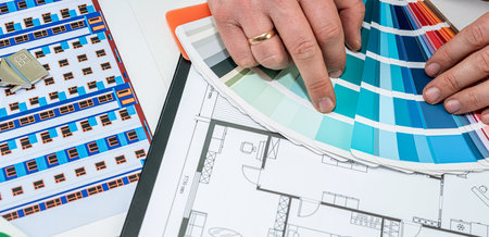 a man's hand chooses a color from a palette on an architectural plan of a new house. repair concept. designer by plan to doの写真素材