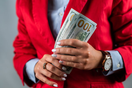 Confident girl pointing to a large amount of dollars in cash in her hands isolated on a white...