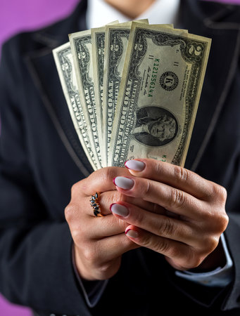 Close-up of dollar banknotes in the hands of a happy business woman isolated on a plain background....