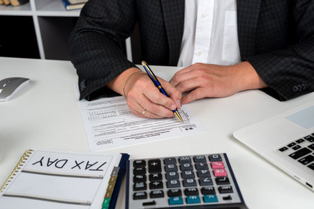 young businessman accounting and filling individual us tax form 1040. Financial difficulty, tax systemの写真素材