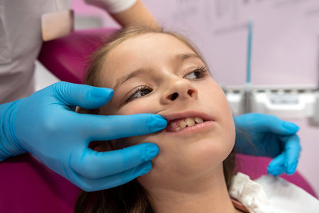 Close-up of little girl with open mouth sitting in dentist's chair. The girl visits the dentist. healthy teethの写真素材