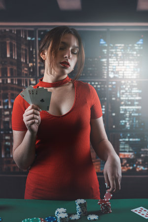 Attractive young woman in a red dress holding a combination of poker cards. poker. Gambling. cards in handsの写真素材