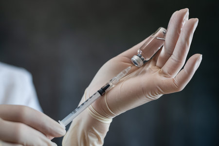 Young female nurse in white uniform mask and gloves holding syringe and liquid vaccine isolated. Concept of medical careの写真素材