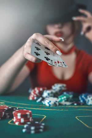 poker player sits at a poker table with cards in her hands and poker chips on the table. poker....