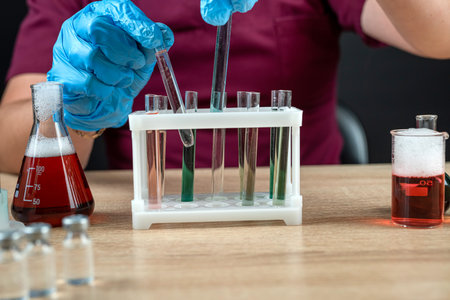 male scientist in lab coat mixing reagents from glass flasks, all for chemistry experimentの写真素材