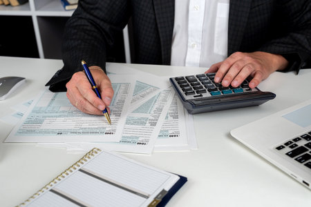 close up of male hand filling US tax form. Accountant working with 1040 form. April, tax for time