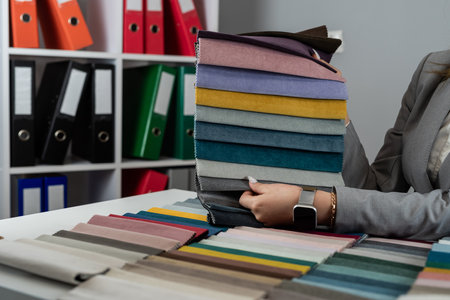 woman choose different color in fabrics catalog for upholstered furniture for home renovation at...