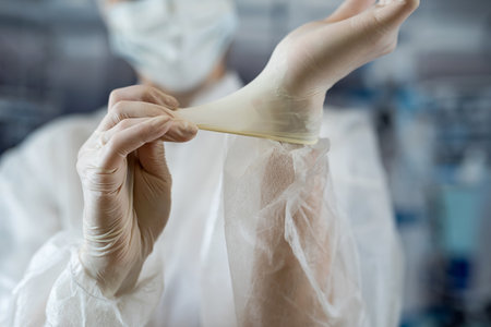 woman doctor wear labcoat putting sterile gloves at surgery. Heathcare worker. Medical conceptの写真素材