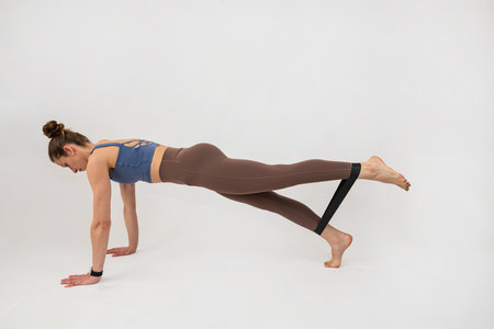 European woman wear sportclothes doing pilates workout with rubber bands isolated on white. Workout...