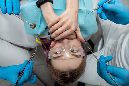 Fear of dentist or fear of the doctor of a young female patient who covers her mouth with her hands. Scared and nervous patient in the hospital.の写真素材