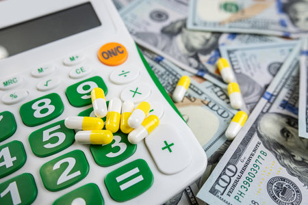 calculator and medical pills lying on us dollar banknotes. Concept of high pharmacy costの写真素材