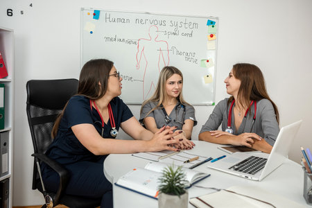 Teamwork of three female nurse and doctor talking sitting at a table in the office of the hospital. Medical workersの写真素材