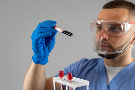 Male doctor wearing uniform mask and gloves look at blood in test tube isolated. Health care, science concept.の写真素材