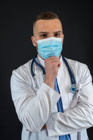 Portrait of caucasian professional doctor in protective cloth mask and gloves with stethoscope isolated. Medical staff health care protection conceptの写真素材