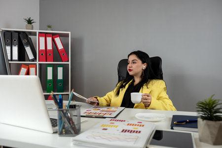 Pretty caucasian business woman working on laptop and financial graph data documents, preparing economic report. Analytical research conceptの写真素材