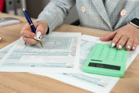 Business woman filling  individual income tax return form, tax documents in office. Deadline