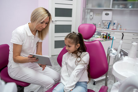 little girl sits at a consultation with a woman at the dentist who records the child's complaints. dentistry child in pediatric dentistryの写真素材