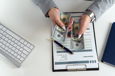 close up woman holding dollars working at office with business graph and chart, investment conept