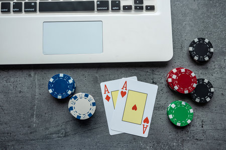 poker playing cards with casino chips on laptop keyboard for online gambling. Top viewの写真素材