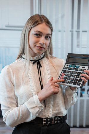 Young charming caucasian woman in suit hold calculator in business cetner, office workの写真素材