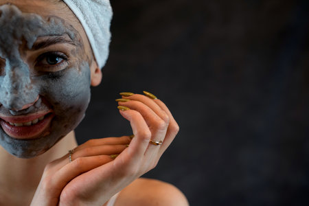 Beautiful girl applying face mask foam bubbles with charcoal oxygen isolated on black background....