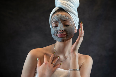 Female face with gray bubble mask as anti aging treatment for perfect skin isolated on black. beauty spa procedureの写真素材