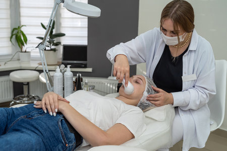 Beautiful young caucasian lady getting   beauty treatment facial peeling with ultrasound device. Cosmetological clinicの写真素材