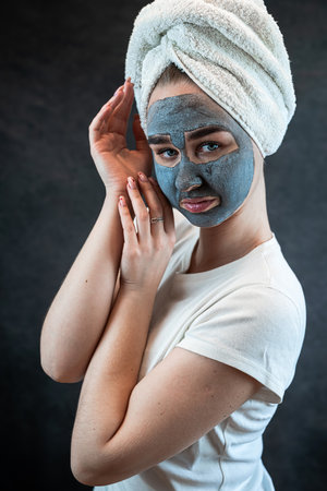 young beautiful woman wear white towel doing beauty wellness treatment with black clay facial mask. Anti aging treatment, skincareの写真素材