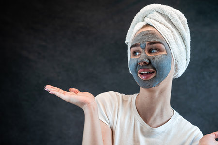 young beautiful woman wear white towel doing beauty wellness treatment with black clay facial mask. Anti aging treatment, skincareの写真素材