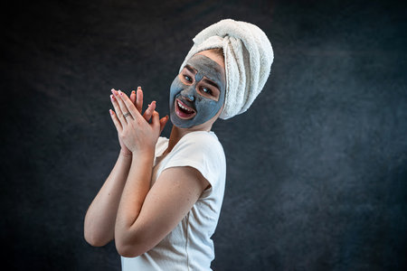 young beautiful woman wear white towel doing beauty wellness treatment with black clay facial mask. Anti aging treatment, skincareの写真素材