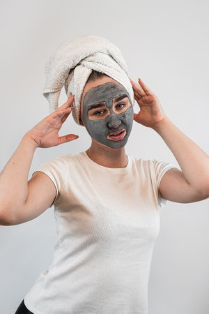 portrait of young woman  getting facial care clay or mud mask isolated on white.  Beauty treatmentの写真素材