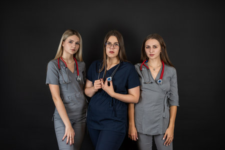 Group of three young female doctor or nurse wear uniform stethoscope isolated on black. Health care conceptの写真素材