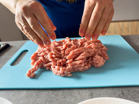 Female hand mixing mince for the dumplings or cutlets at home. Uncook raw foodの写真素材