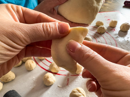 Unrecognizable female hands sculpts dumplings food from dough and potatoes in the kitchen. Homemade raw foodの写真素材