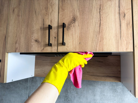 female hand in yellow rubber gloves, using a rag cleaning the wooden top kitchen. Housework conceptの写真素材