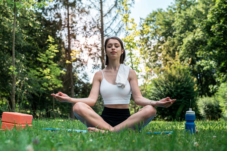 Young caucasian slim woman doing stretching or yoga relaxing exercise at part, sport on nature. Healthy lifestyleの写真素材
