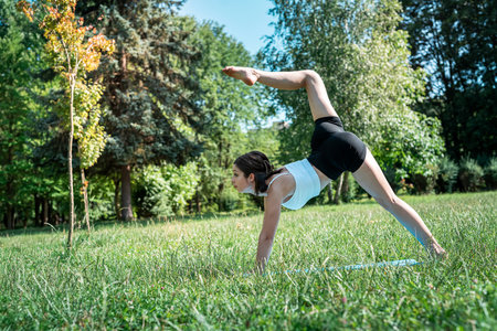 Slim pretty woman practicing relax yoga or pilates at nature. Time for sport at summer morning in the parkの写真素材