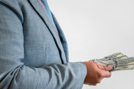 Man in suit holding and counting cash us dollar isolated on gray. Finance conceptの写真素材