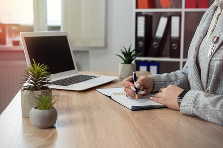 female web designer making notes in notepad, use lapton on office workplace. Online elearning conceptの写真素材