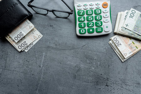 Polish zloty banknotes PLN currency in black wallet wirh calculator glasses in grey desk. Financial accounting conceptの写真素材