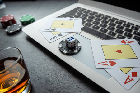 poker playing cards with casino chips on laptop keyboard for online gambling. Top view