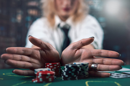 beautiful girl dealer in a shirt with a black tie deals chips at the poker table. the dealer watches...