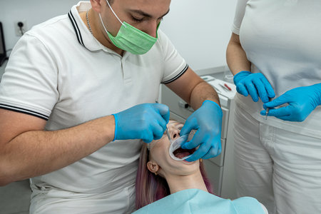 male dentist treats a patient's teeth and a female assistant helps him. healthy oral cavity. dentistryの写真素材