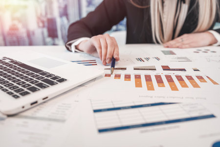 Beautiful caucasian business woman wear suit work with financial graph nad chart paper document on table at office. Finance annual report, paperworksの写真素材