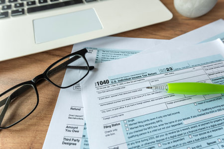 1040 U.S. individual income tax form with glasses pen and online work with laptop on desk. Deadlineの写真素材