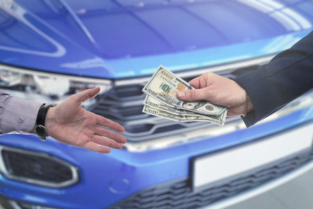 Business man spend dollar money to buy or rent new car at modern showroom. Concept of purchase new autoの写真素材