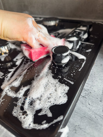 close up female hand cleaning with rag and white foam gas stove in the kitchen. Housekeeping conceptの写真素材