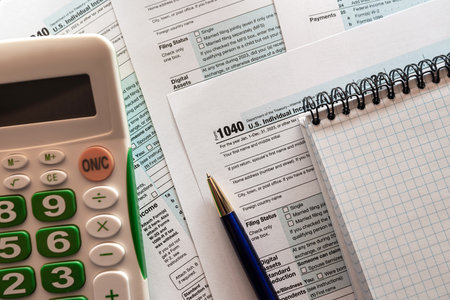 1040 US tax form with pen and calculator on office desk. Taxes burdenの写真素材